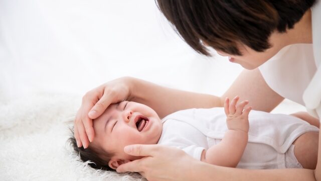 赤ちゃんの熱をはかる母親の画像